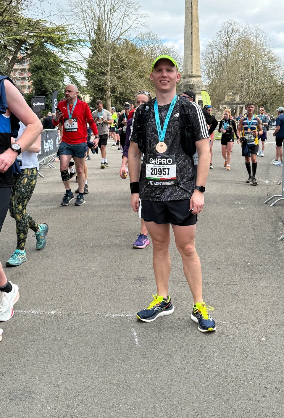 Graham at the Bath Half finish line, smiling with his medal and race bib 20957