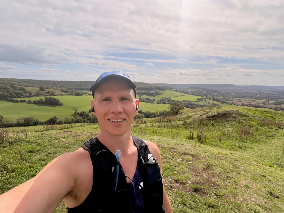 Graham on a grassy hillside in a blue cap and running vest